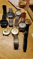 Overview of seven watches on wooden surface