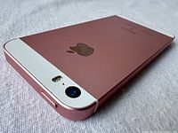 Close-up of the rear bottom corner showing rose gold casing and camera module with flash.