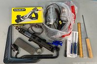 Top view of all items in box showing the Stanley hand plane box, handheld lamp, cutter sharpening block, screwdrivers, scissors, and ruler.