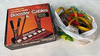 Photo showing the boxed jumper cables and the loose cables inside a plastic bag.