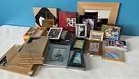 Overview of multiple picture frames including boxes and loose frames in various sizes and colors on table