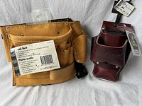 Close-up of two leather tool belts side by side, one dark brown Occidental with multiple compartments, one yellow suede adjustable with label showing 11 pockets and features.