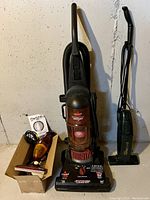 Three vacuum cleaners including Bissell PowerForce Bagless Turbo upright, a smaller green upright vacuum, and a handheld vacuum with accessories