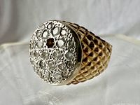 Angled front-view showing round pave diamond top with one missing center stone and textured band