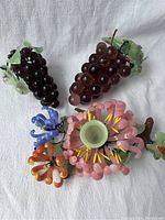 Photo showing two glass grape clusters with green leaves and the floral candle holder with petals and a candle cup