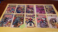 Full view of 10 Marvel comic books laid on table including Spider-Man, The Invaders, and Battlestar Galactica. All covers are visible showing a variety of classic Marvel artwork.