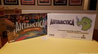 Photo showing two sealed Antarctica board games. The left box is titled 'Antarctica: Global Warming' with character illustrations. The right box is titled 'Antarctica' with a continent map graphic.