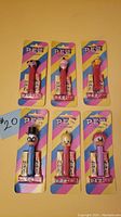 Front view of six vintage PEZ dispensers in original packaging, featuring six different cartoon animal heads on pink dispensers.