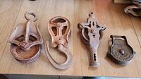 Front view of four cast iron antique farm pulleys with visible rust on wooden surface