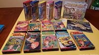 14 Magic School Bus VHS tapes, including various titles with colorful illustrated covers, and two hardcover Magic School Bus books