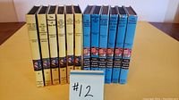 Front view of all 12 hardcover books in set, 6 Nancy Drew with yellow covers, 6 Hardy Boys with blue covers.