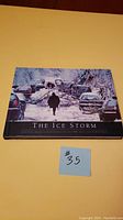 Cover of The Ice Storm hardcover book showing a snow-covered street with cars and fallen tree branches. Image captures the theme of the book.