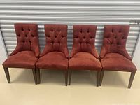 Full front view of four tufted fabric dining chairs in burgundy upholstery with wooden legs