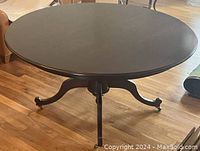 Top view of round wooden dining table with uniform dark finish showing no leaf inserted.