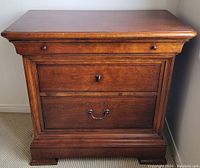 Front view showing three drawers and wood finish