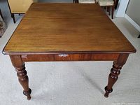 Front view of rectangular wooden dining table top and turned legs