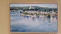 Framed oil on canvas painting showing waterfront town with boats and buildings, signed by artist
