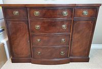 Front view of the full mahogany buffet showing side cabinets with doors and drawers, and center curved drawers with brass hardware.