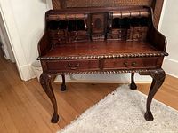 Full front view of carved wood desk showing upper hutch, lower drawers and cabriole legs