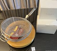 The BBQ grill basket sitting on three yellow charger plates, next to three stacked white boxes containing the wine funnels.