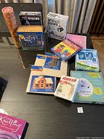 Various new kids games and science kits such as weather science, crystals, wooden craft kits and puzzles, all boxed, unopened and assorted on a table.