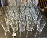 Group of 30 clear glass beer glasses displayed on a reflective surface, arranged in rows showing consistent size and shape.