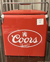 Front view of red Coors metal cooler with logo and handle on top, showing good condition and design features.