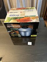 Photo of boxed Kitchen Magician Pot showing front with product image, dimensions, and branding.