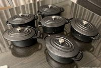 Six mini cast iron dishes with lids shown from above on a table