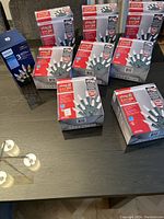 Nine boxes of Christmas mini light sets arranged on table including 8 Sylvania Stay-Lit and 1 Philips box