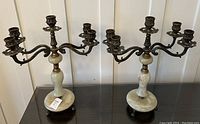 Full view of the pair of alabaster and bronze candelabras showing their size and form on a black surface.