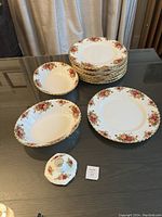Full set showing stacked dinner plates, two bowls, and a ceramic candle stick holder on a dark table.