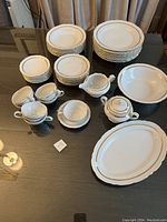 Overview of entire vintage Bohemian Caprice china set showing plates, cups, saucers, sugar bowl, creamer, serving bowl, and platters on table.