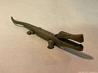 Side view of the brass crocodile nutcracker showing detailed scales and open mouth.