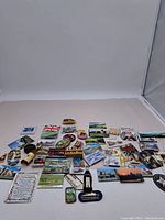 Overall view of assortment of fridge magnets laid out flat on surface showing diverse designs including landmarks, flags, figurines, and plaques.