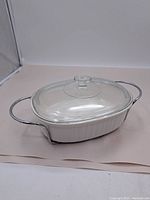 Photo of Corning Ware casserole dish in metal holder with glass lid on showing overall condition and design