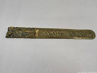 Full view of the cast brass ornament showing the entire length with ornate detailing.