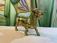 Side view of the heavy brass bull figurine showing muscular build and curved horns.