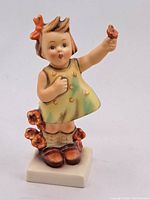 Front view of the Hummel figurine showing the girl holding a flower, with detailed dress and flower decorations.