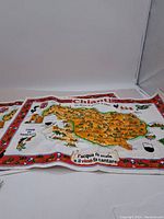 Full view of one tea towel showing a colorful map of the Chianti region of Italy with wine glasses and grapevine decorations.