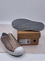 Front and sole view of one shoe with shoebox underneath showing 'native' branding on sole and child's size label visible on the box.