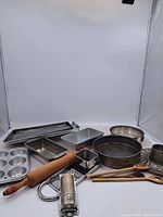 Full view of all kitchenware and baking trays showing the variety of metal baking trays, wooden utensils, and graters.