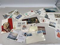 Overview of assortment including postcards, envelopes, stamps, and covers laid out on a table, showing variety of designs and content.