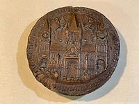 Top view of round metal paper weight showing detailed cathedral architectural design with text encircling the edge.