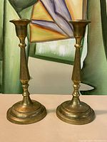Front view of two vintage brass candlesticks showing shape and finish.