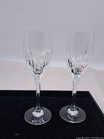 Pair of clear Mikasa crystal stem glasses displayed together on a black surface.