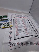 Tea towel showing Scots Tongue words with floral border, new and folded in packaging