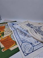 A set of three souvenir tea towels featuring distinct regional prints laid out partly overlapping on a surface.