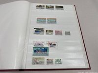 Open page of the stamp album showing a selection of assorted vintage stamps depicting landscapes and trains