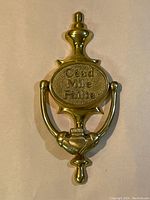 Front view of the vintage brass door knocker with Gaelic text and Claddagh symbol.